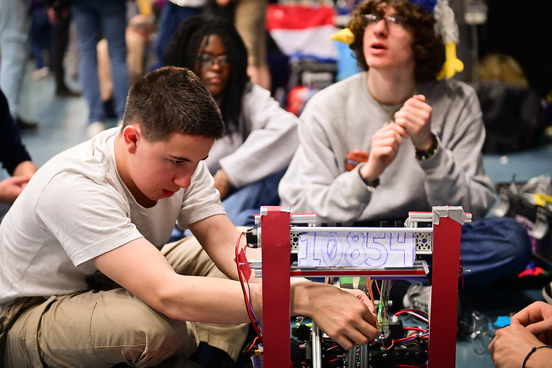 Un élève ajuste son robot pour la FIRST Robotic Competition 